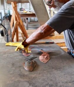 An artist paints a detailed face on a flat surface using a brush.