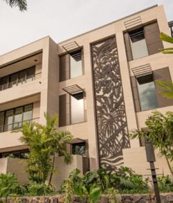 Modern multi-story residential building with decorative facade and greenery.