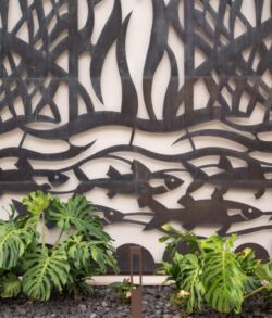 Intricate metal wall art with leafy plants below.