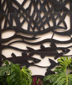 Decorative wall art with fish and water motifs above green plants.
