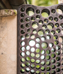 Decorative copper window insert Close-up of a black perforated metal panel with circular holes.