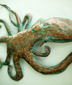 Copper oil lamp sculpture A rustic metal sculpture of an octopus with detailed tentacles.
