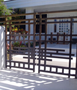 Brass man gate Decorative black metal gate with geometric patterns at a white-walled entrance.