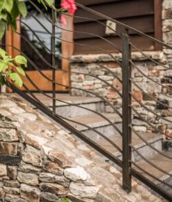Brass hand railing Modern metal railing on stone staircase with wooden house exterior.