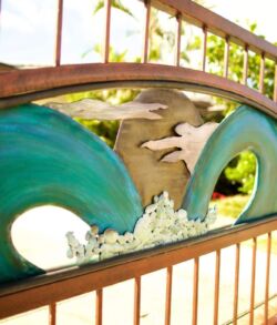 Decorative metal panel with ocean wave and bird motifs on a railing.