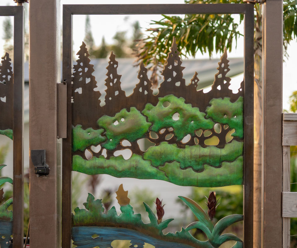 Decorative garden gate with metal art of nature scene.