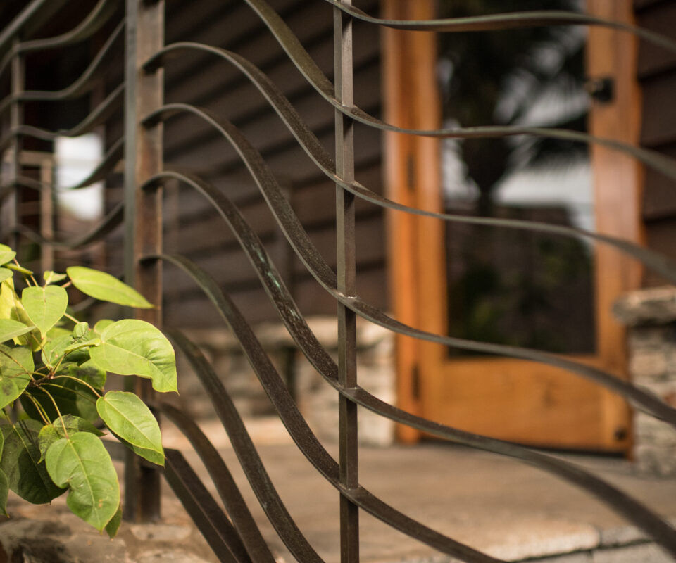 Decorative metal railing with a wooden door in the background.