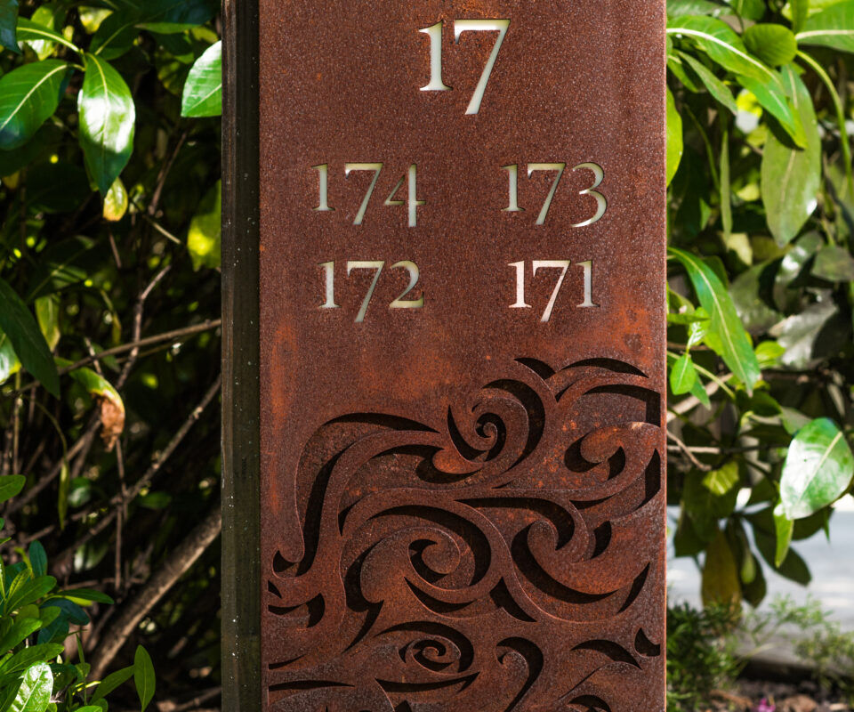 Rustic metal garden marker with numbers and decorative cutouts.