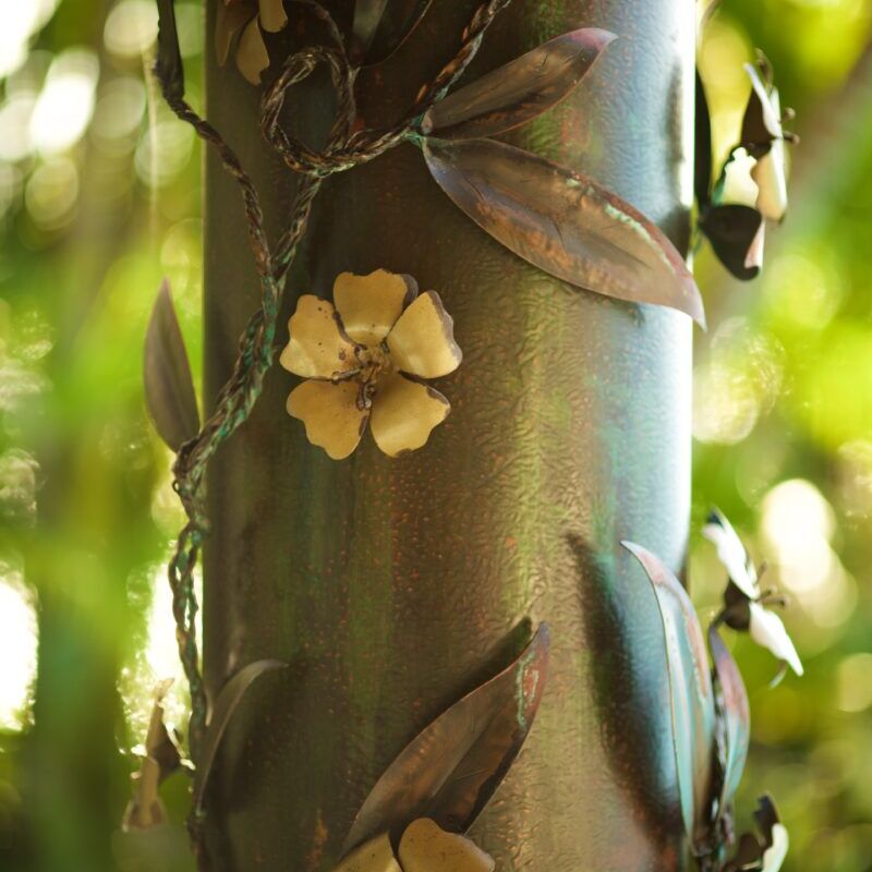 Close-up of a metallic pole decorated with small flower sculptures.
