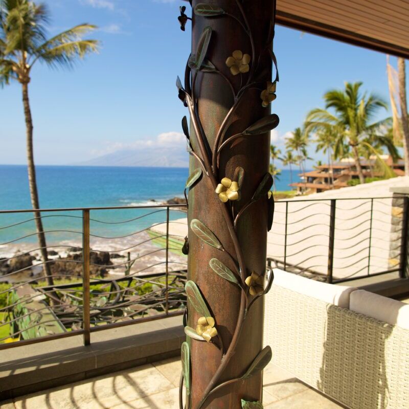 A tropical outdoor scene with a decorated palm tree and ocean view.