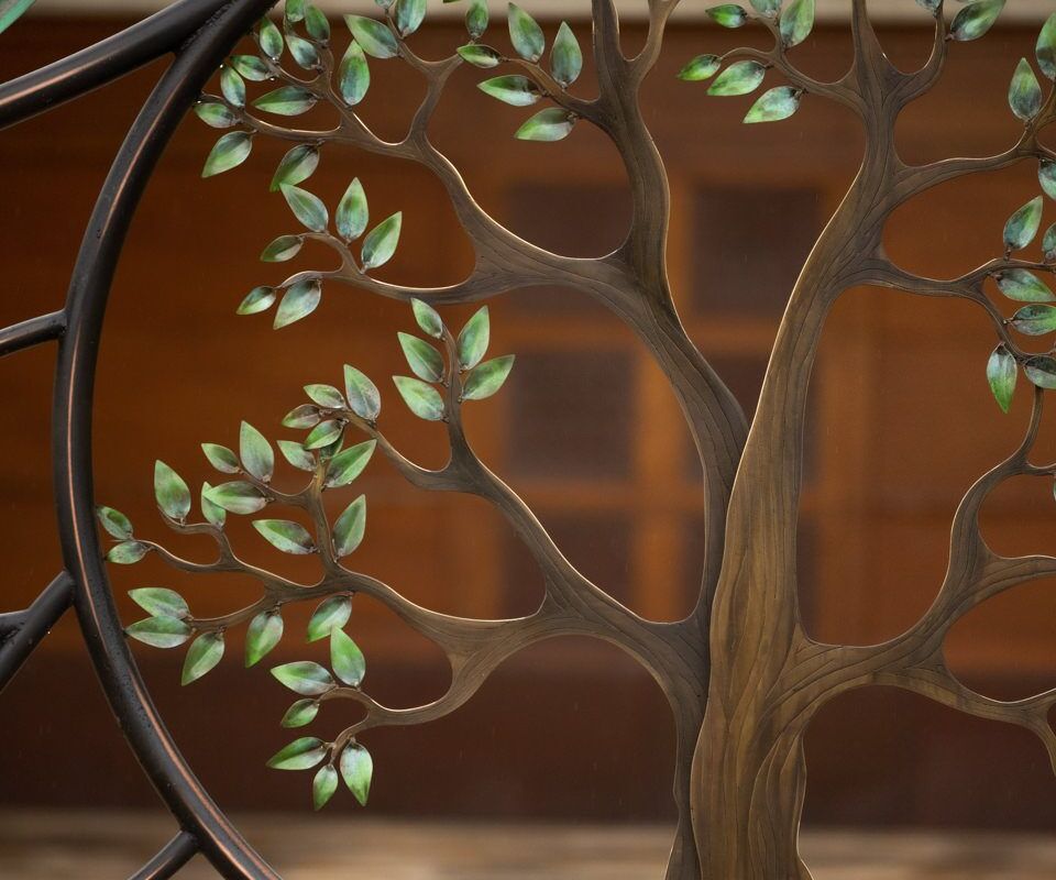 Decorative metal tree sculpture with leafy branches on a wooden background.
