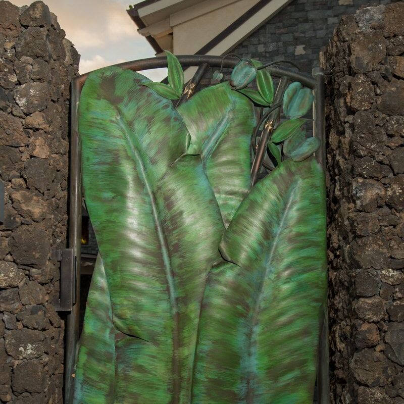 A green, textured gate with a leaf-like design between stone walls.