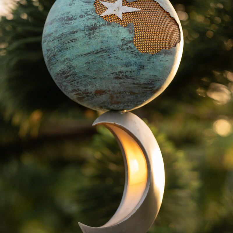 A decorative globe hanging above a crescent moon ornament.