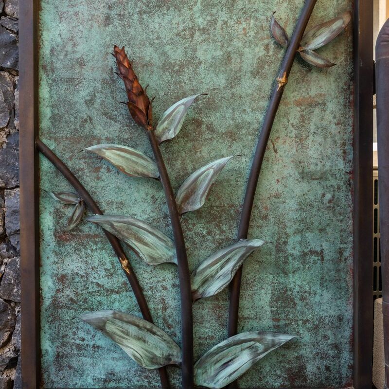 Metal art panel featuring a tall plant with leaves and seed pods.
