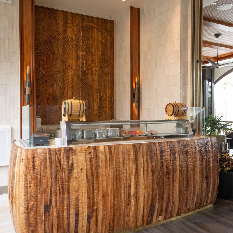 Elegant wooden reception desk with a glass countertop in a modern space.