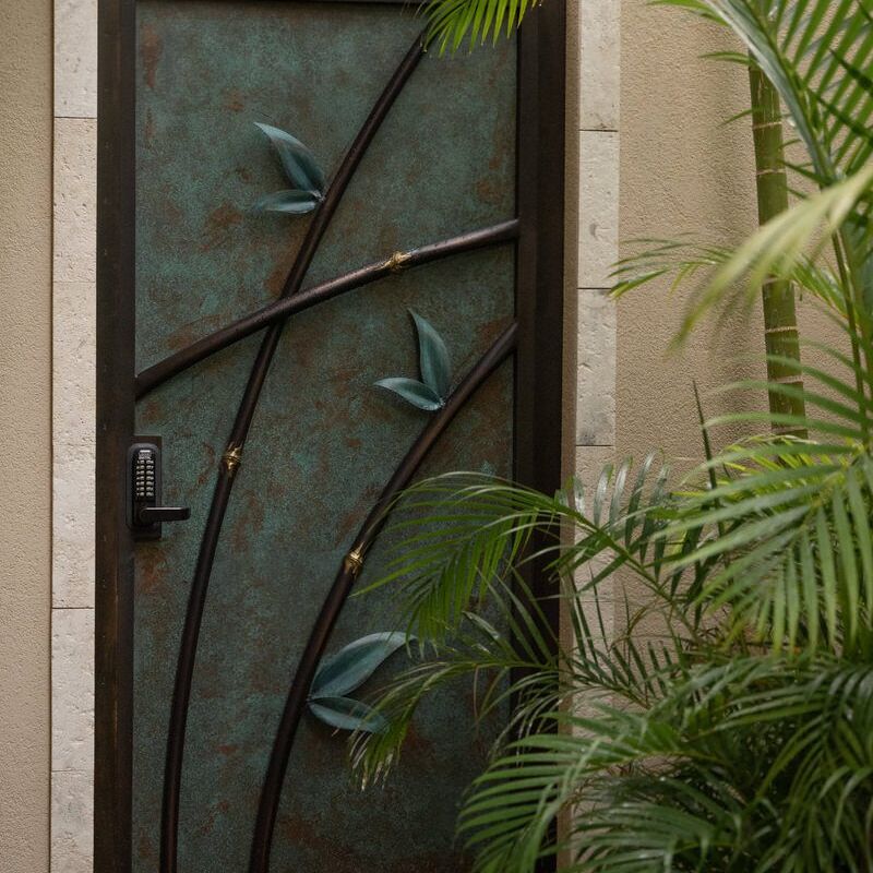 Decorative glass door with leaf designs, surrounded by plants.