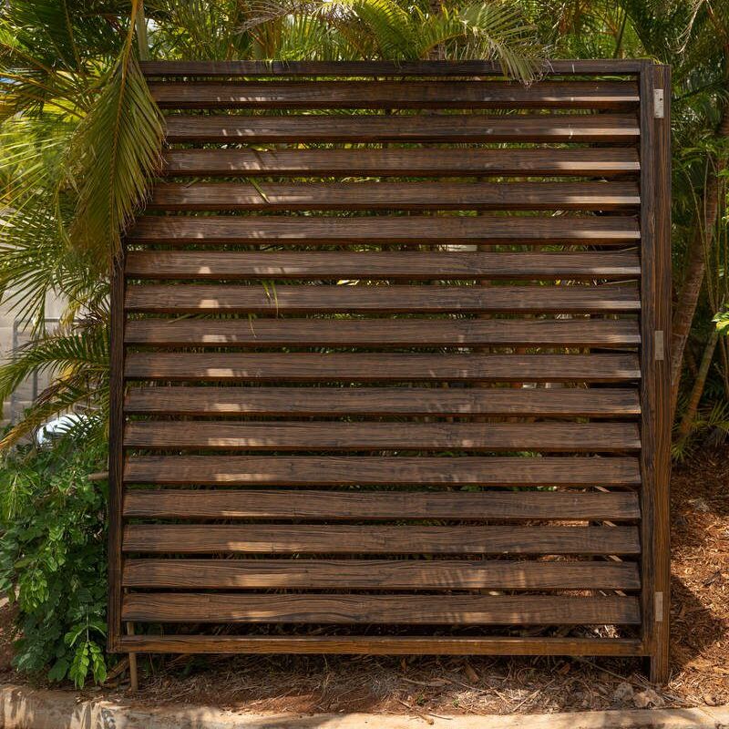 Wooden slatted panel leaning against a tree outdoors.