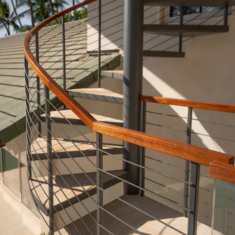 Modern staircase with wooden handrails and metal cables.