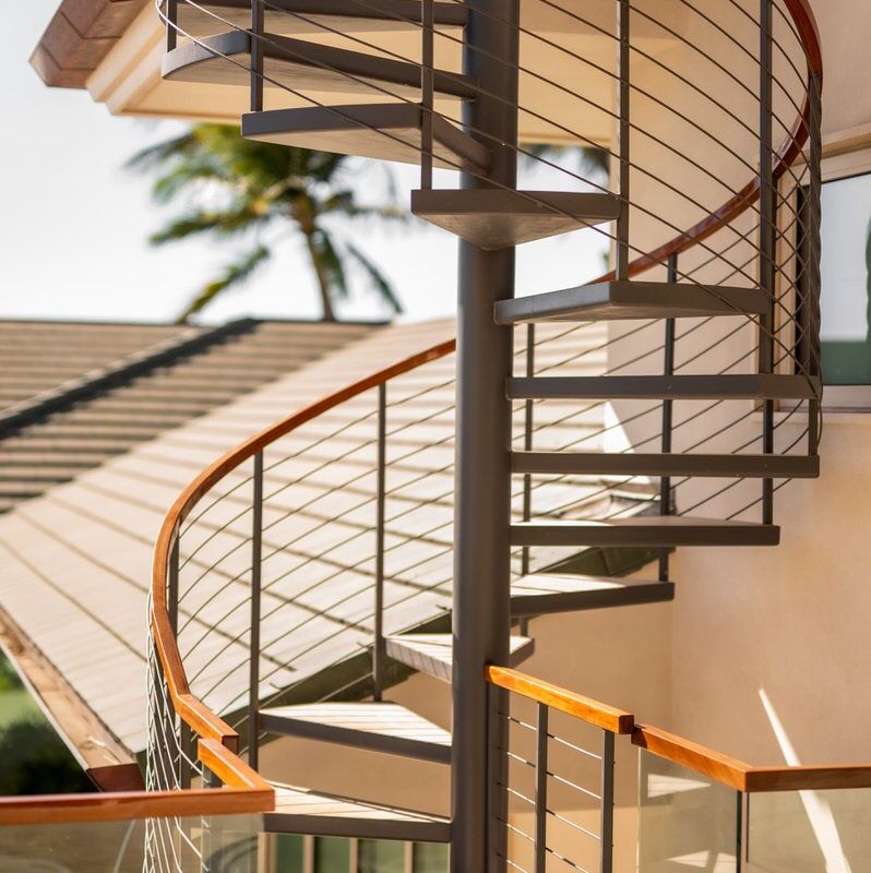 Modern spiral staircase with wooden handrails and metal steps.