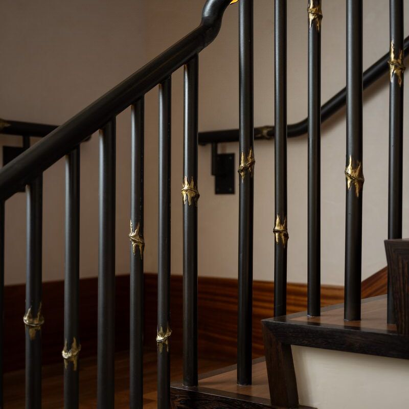 Dark wooden staircase railing with golden accents in a classic interior.
