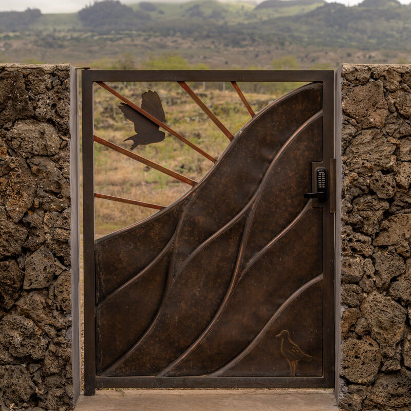 Metal gate framed by lava rock walls